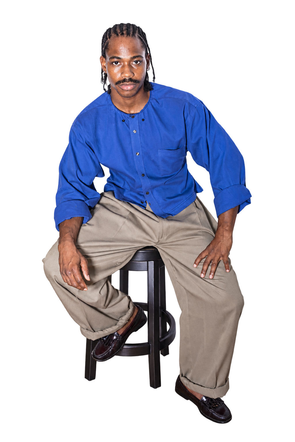 Terrill Jefferson seated on a black stool, wearing a blue shirt and relaxed tan trousers